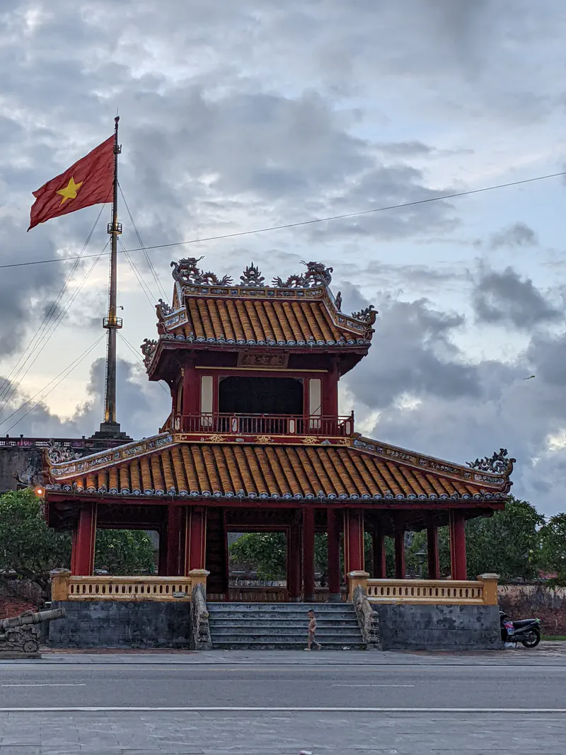 Historic red and yellow pavilion with the Vietnamese flag flying above in Huế.