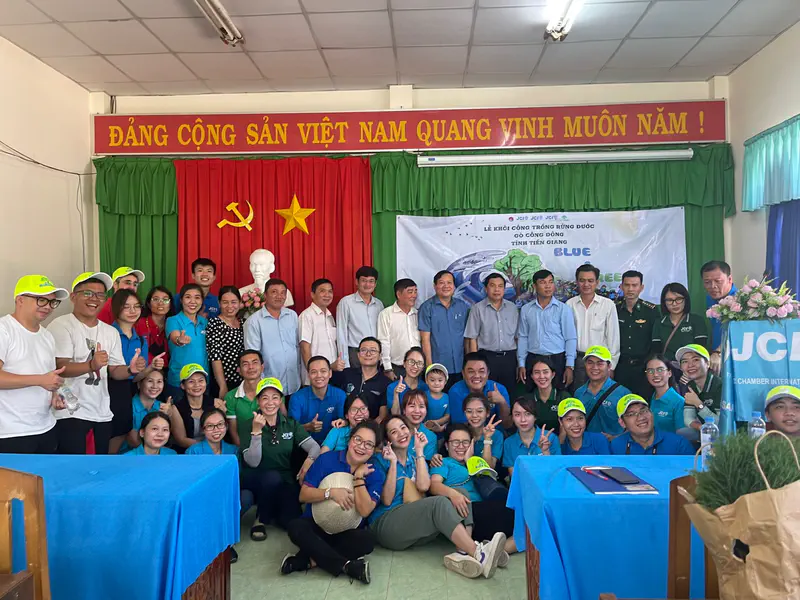 Large group photo of participants and officials indoors at a Blue & Green community event in Vietnam.