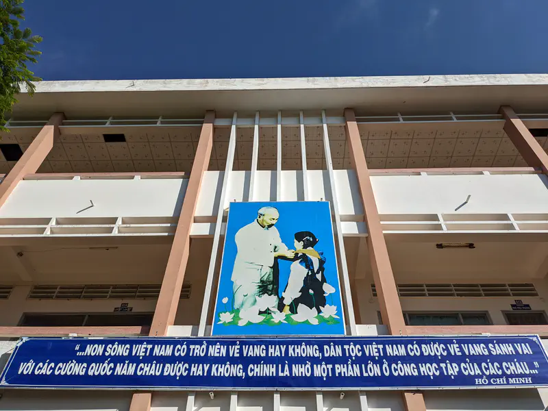Building facade with a mural of Ho Chi Minh and a child, with a Vietnamese quote displayed below.