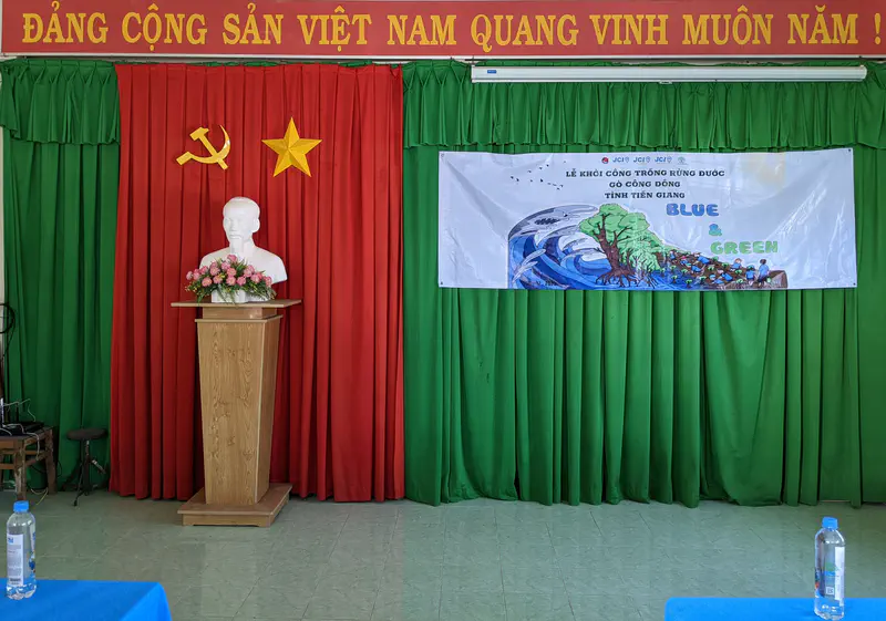 Stage with a bust of Ho Chi Minh, red and green curtains, and a Blue & Green event banner.