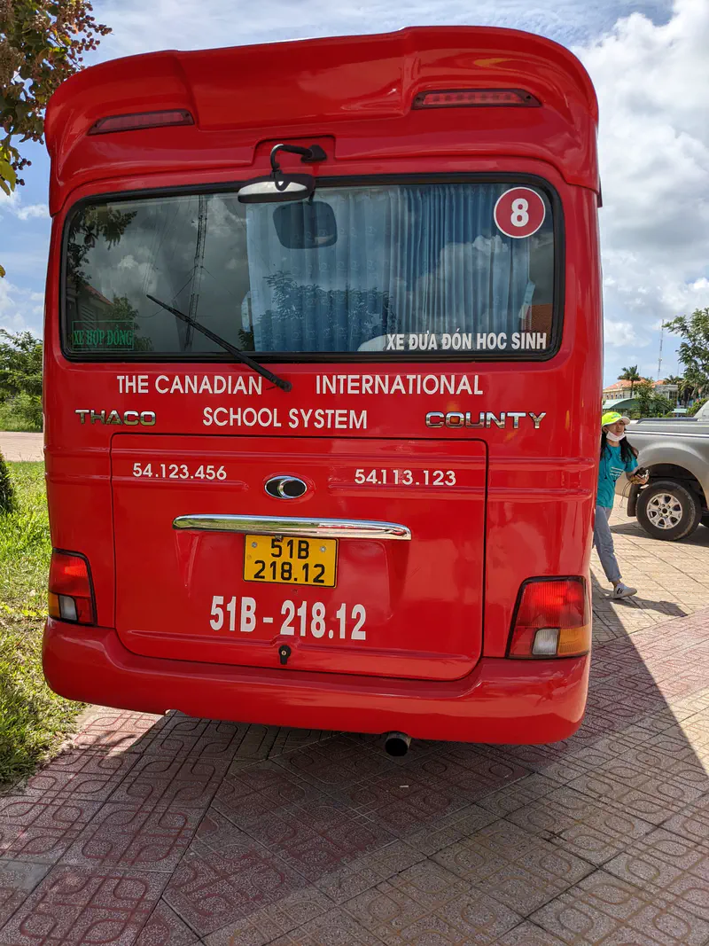 Back of a red bus labeled The Canadian International School System with license plate 51B-218.12.
