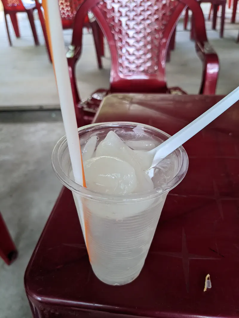 Plastic cup filled with iced nipa palm fruit drink on a red table.