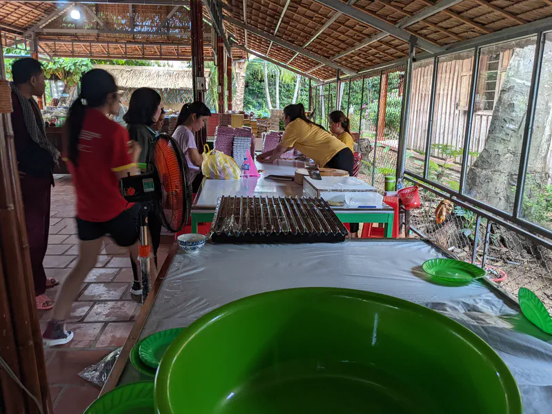 People working at a table making traditional coconut candies in a rustic workshop.