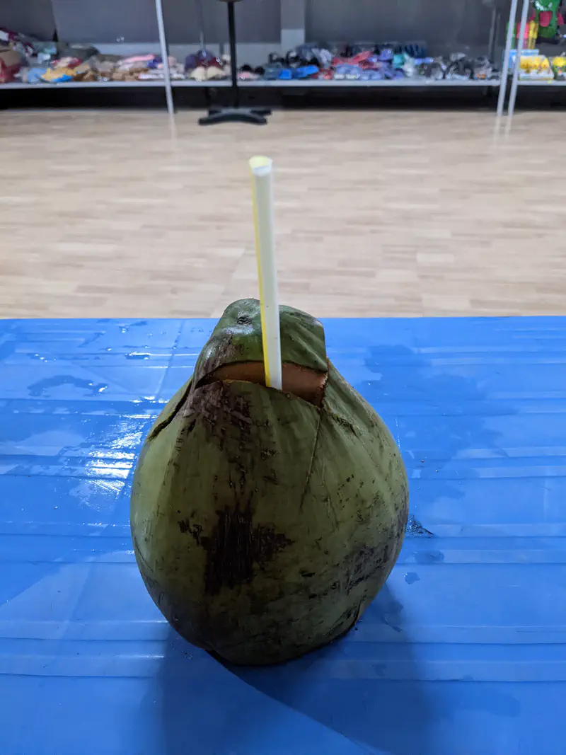 Fresh green coconut with a straw inserted for drinking.