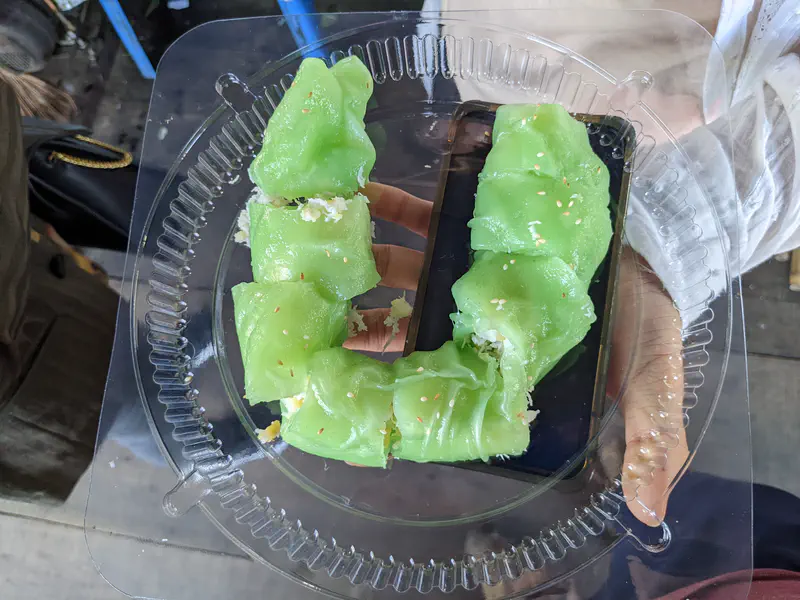 Tray of green rice cakes filled with shredded coconut.